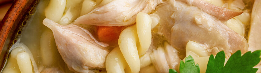Top view close-up of chicken spiral noodle soup panoramic