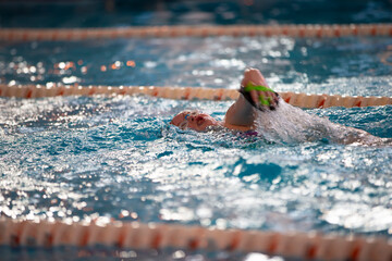 Child athlete swims in the pool. Swimming section.