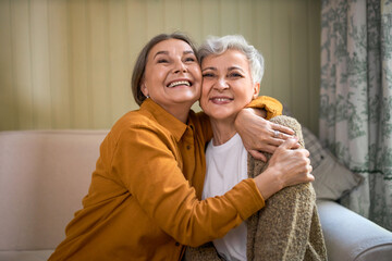 Happy to see you. Joyful gray haired middle aged female hugging her sister, expressing positive emotions. Two beautiful overjoyed retired women embracing each other, having good time together