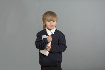 the boy is standing with a book in his hands, wearing a white shirt and a blue sweater