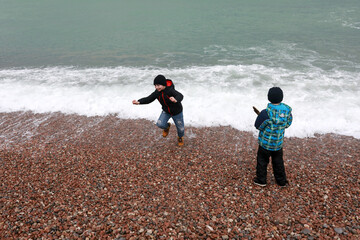 Boys running away from wave on Gurzuf beach