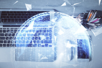 Business theme hologram drawings over computer on the desktop background. Top view. Multi exposure....