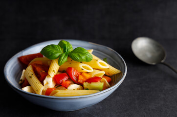 Vegetables pasta salad. Homemade pasta salad with tomatoes, vegetables and mozzarella cheese in a bowl.