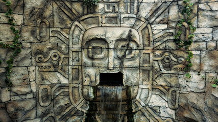 Stone wall in the jungle. Head mask and waterfall from the mouth. Minsk Zoo