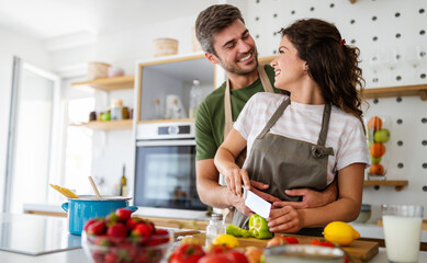 Obraz na płótnie Canvas Happy young couple have fun in kitchen while preparing healthy organic food