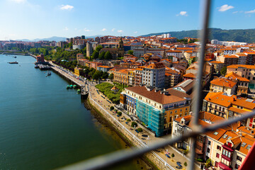 Portugalete from Vizcaya Bridge. Picturesque modern cityscape on bank of Nervion river with ancient Basilica de Santa Maria, Spain..