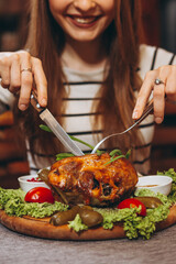 attractive woman with a fork and a knife cuts a large portion of fried meat at a table in a restaurant