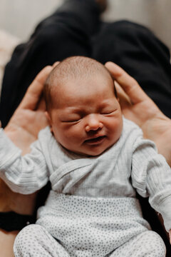 home photos of a newborn baby in the arms of one parent