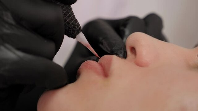 Close-up of the process of applying permanent makeup to the lips.