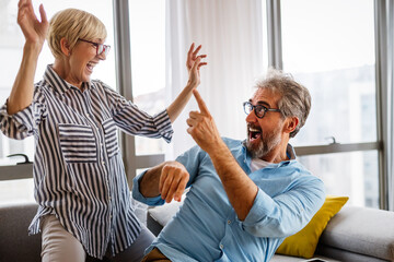 Obraz premium Cheerful senior couple enjoying life together, having fun at home