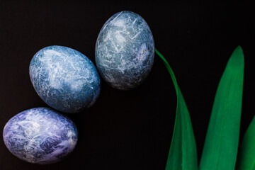 Easter eggs painted in the form of planets in space in blue on a black background. Marble dyes for Easter painted in hibiscus