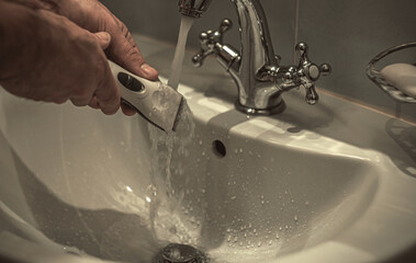 Washing under the tap of the hair clipper. Home barber.