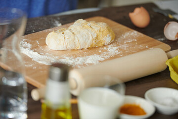 Dough on a wooden table with flour, eggs, close-up. Ingredients for bread, homemade baked goods, pizza.
