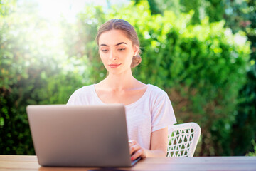 Attractive young woman with her laptop sitting at desk in the balcony at home
