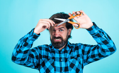 brutal man in checkered shirt has long beard cut hair with scissors, hairdresser
