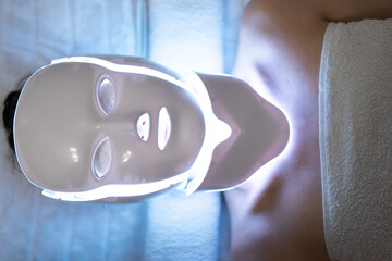 Woman with led light therapy facial and neck beauty mask photon therapy. Home skincare and me time...