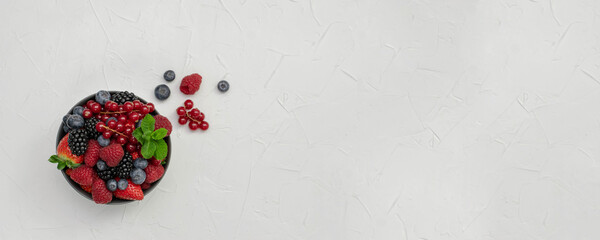 Banner of ripe sweet different berries in bowl on stone table. Harvest Concept.