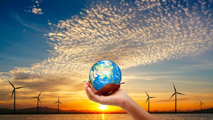 Hand holding the earth on dry leaf. turbin with sun set background. save the earth concept.