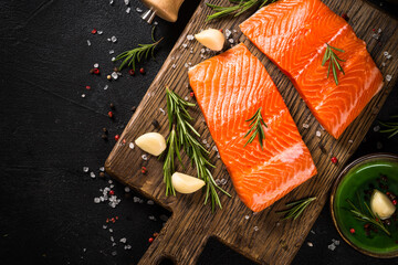 Salmon fish with ingredients at black table.