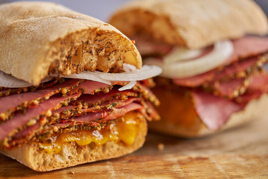 Thin cut pastrami sandwhich with delicious meet on baguette bread with chedder cheese, onion