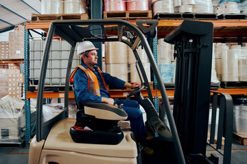 Industrial driver arranging boxes with forklift truck at manufacturing industry