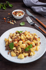 Stewed pasta with minced beef and vegetables, macaroni in Navy style on a plate. Dark wooden background. Copy space.