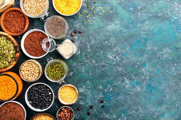 Various organic superfoods, beans, grains, cereals, legumes, seeds in reusable cans and jars. Copy space top view. Blue background