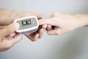 Fingertip pulse oximeter on the finger of young woman measuring heart rate (pulse) checking oxygen...