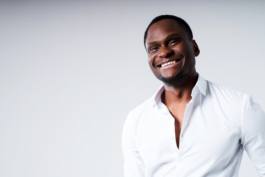 Happy dark-skinned man in white shirt with open collar smiling looking at camera