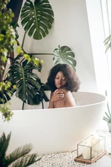 Dark-skinned woman relaxing in a bath and washing her body © zinkevych