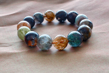 Quartz with inclusion bracelet on cloth background.  Copy space is at the bottom of the bracelet.