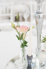 Close-up of a wedding dinner table at reception. Fresh flowers and candles on mirros plate. Wedding decorations.