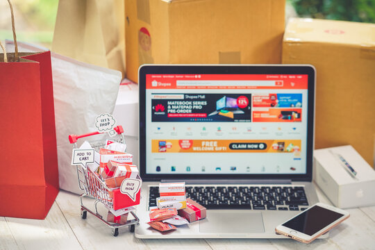 BKK - May 30, 2020 : shopping online concept with soft focus on the shopping cart's bubble wrote ADD TO CART. Parcels in the trolley. On the blurred screen is Shopee, 1 of the popular marketplace app