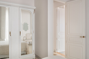 Interior of classic style bedroom. Vintage wardrobe with mirrors and cozy bed in reflection