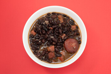 black beans with meat and sausages in white bowl