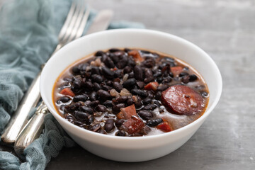 black beans with meat and sausages in white bowl