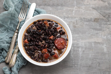 black beans with meat and sausages in white bowl