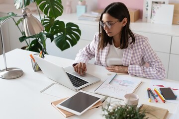 Indian mixed-race beautiful businesswoman working on a new project on her workplace using laptop at the office.