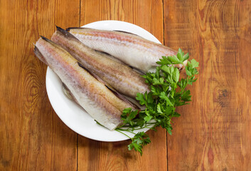 Alaska pollock carcasses on dish on rustic table, top view