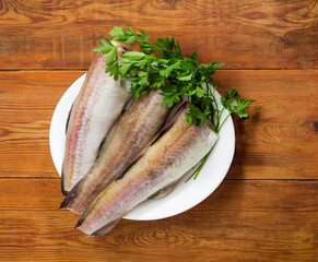 Alaska pollock carcasses on dish on rustic table, top view
