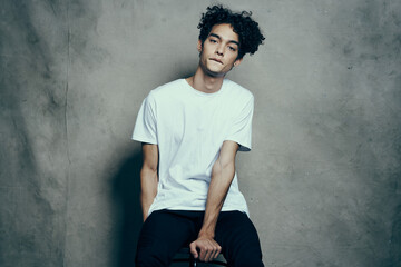 cute guy with curly hair sitting on a chair studio