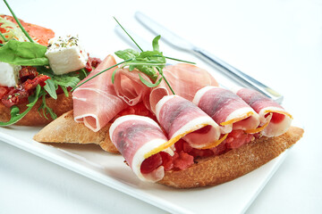 Set of delicious Italian bruschettas with ham, ham, tomatoes, salmon and cheese served with a glass of wine