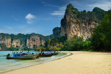 long tail boat, in white sand beach in  andaman sea with view of limestone island 