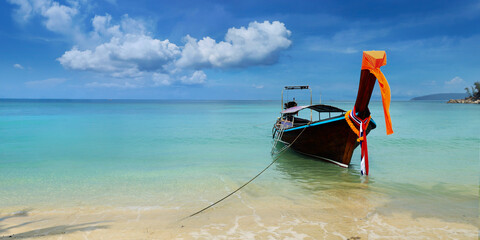 long tail boat, in white sand beach in  andaman sea with view of limestone island 