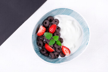 Yogurt with black cereals and strawberry served in the bowl. Top view. Breakfast meal