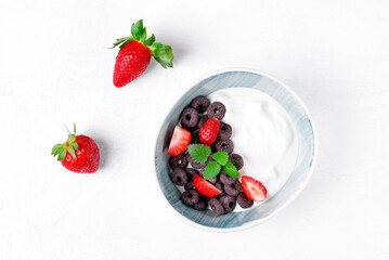 Yogurt with black cereals and strawberry served in the bowl. Top view. Breakfast meal
