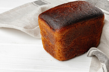 Loaf of rye bread on white wooden table