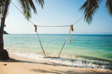 Swing on a tropical beach, beautiful summer landscape. Beach with palm trees and blue sea