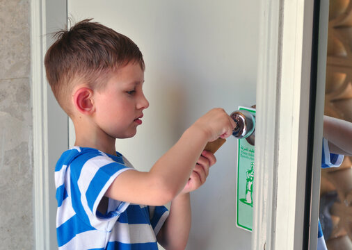 Little Kid With A Key Opening A Door Of Hotel Room