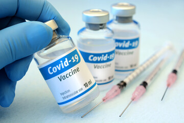 Doctor as vaccinator in vaccination center shows vial with vaccine against Corona virus or Covid-19